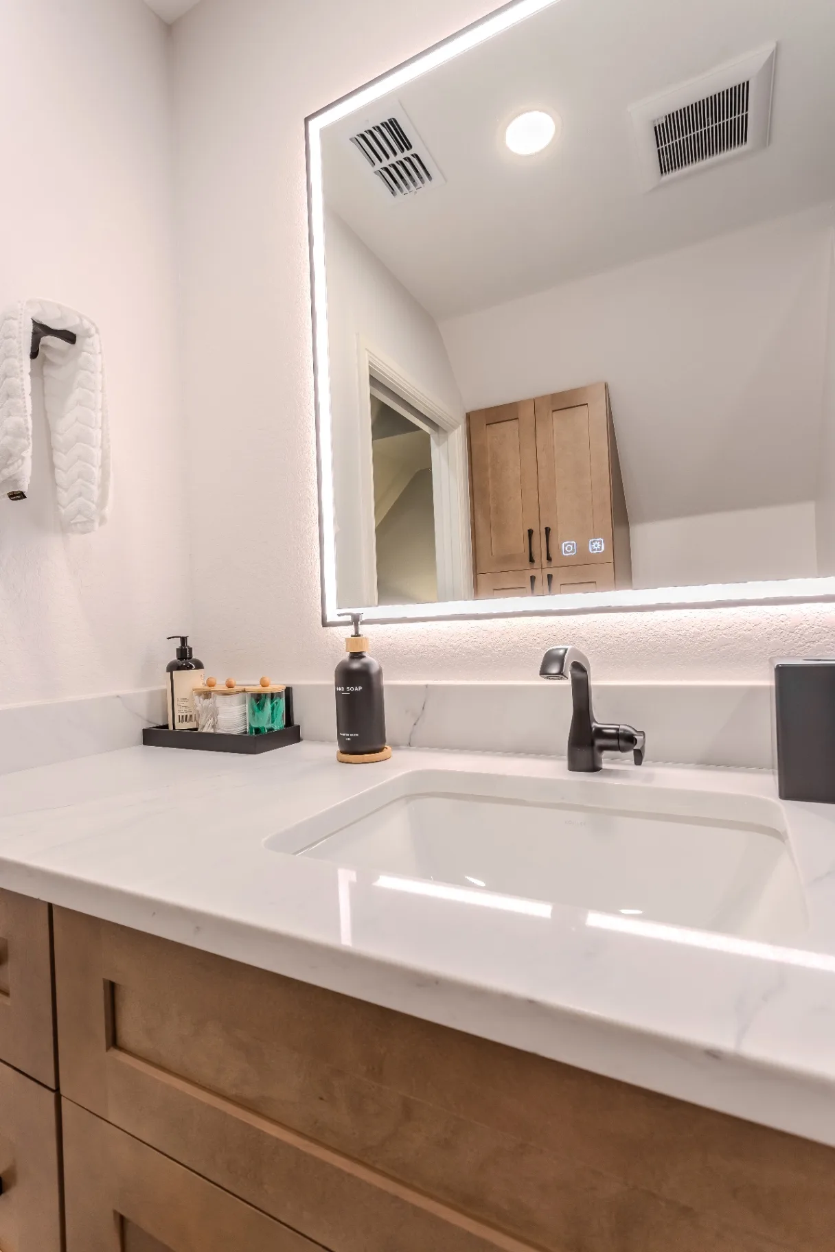 Quartz vanity top with undermount sink, matte black faucet, and backlit LED mirror in the Keller bath remodel
