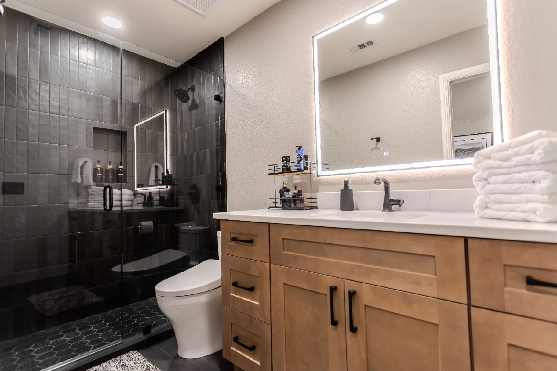 Second full bath with frameless glass walk-in shower, charcoal tile walls, and hexagon mosaic shower pan