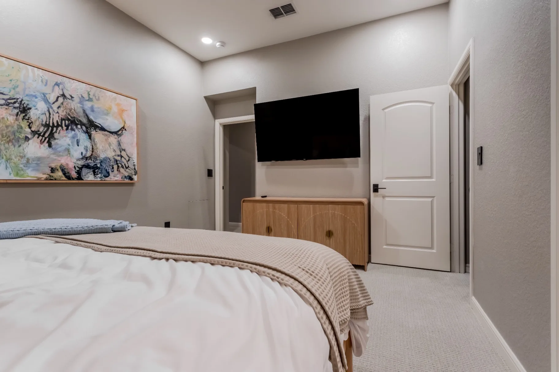 Second view of the remodeled bedroom with wall-mounted TV, oak console, and new interior doors
